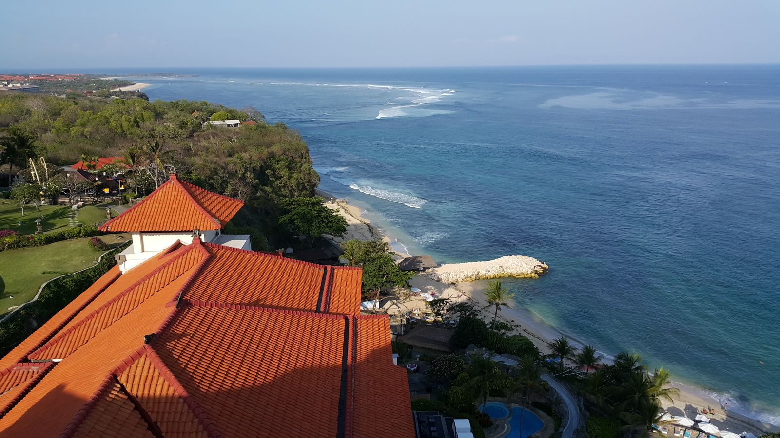 Aerial view of a Bali coastal resort with red roofs above the ocean