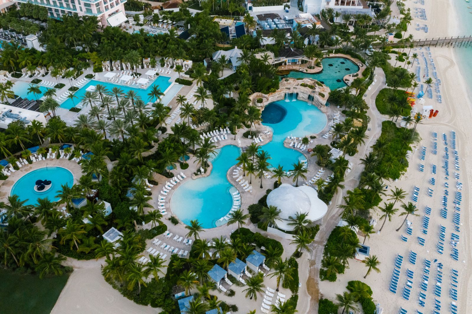 Aerial view of a luxury beachfront resort with pools and palm trees