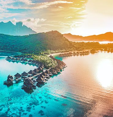 Overwater bungalows in a turquoise lagoon at sunset